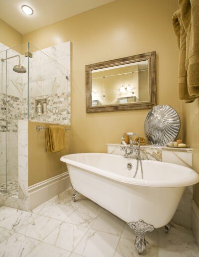Elegant bathroom with a claw-foot tub, walk-in shower, and marble floors.