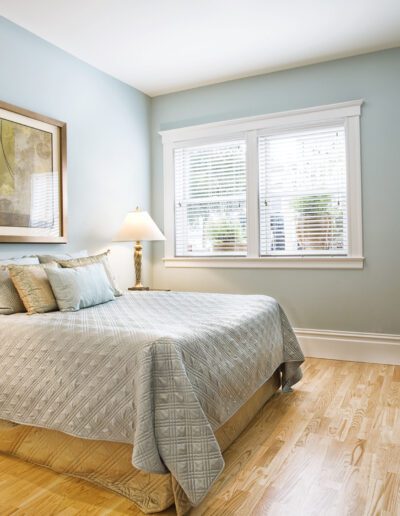 A neatly arranged bedroom with a double bed, two bedside tables with lamps, and light blue walls.