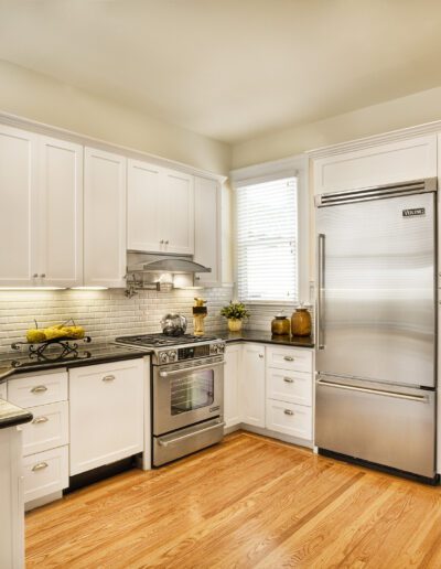 Bright kitchen with white cabinetry, stainless steel appliances, and hardwood floors.