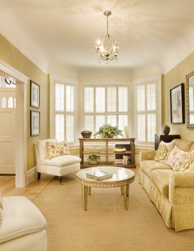 Well-lit traditional living room with beige walls, elegant furniture, and a chandelier.
