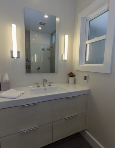 A modern bathroom with a floating vanity, vessel sink, and vertical wall sconces flanking a mirror.