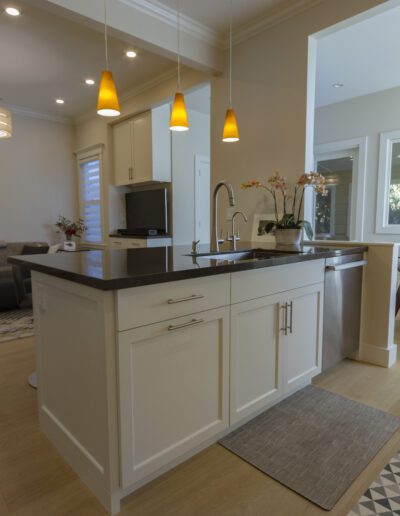 Modern kitchen interior with an island, pendant lights, and stainless steel appliances.