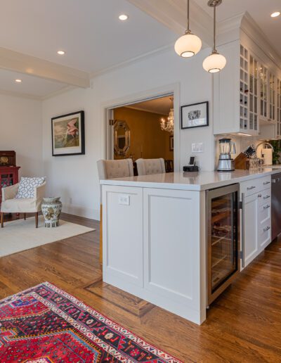 Elegant kitchen opening into a cozy living area with hardwood floors, white cabinetry, and oriental rugs.