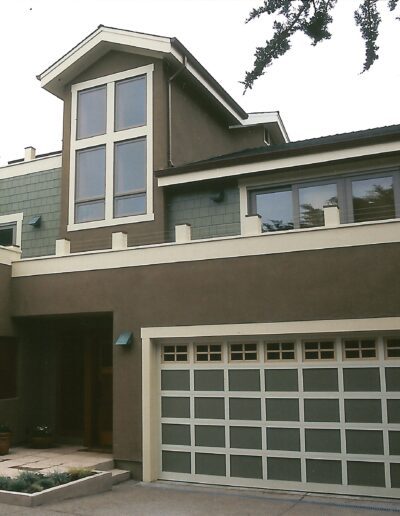 Modern two-story house with a large garage door and a combination of stucco and wood siding.