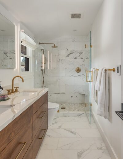Modern bathroom with a double vanity, marble walls and floor, and a freestanding bathtub.
